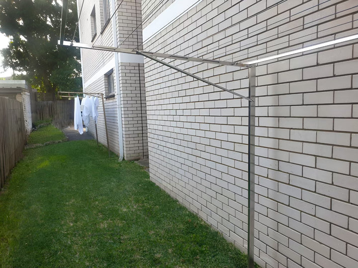 Eco 240 316 Stainless Steel Clothesline installed using standard ground mount kit on grass area - against brick wall