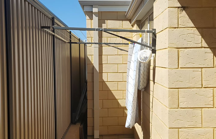 Eco 150 clothesline in use to dry sheets, installed on brick wall